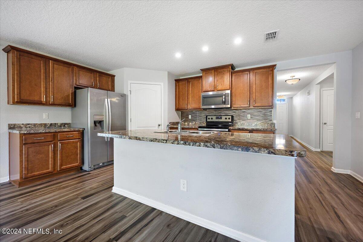 65053 Lagoon Forest Drive Yulee, FL 32097 - Photo 5 of 19 a kitchen with stainless steel appliances granite countertop a refrigerator a stove and a microwave oven