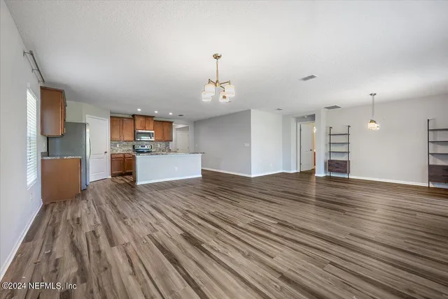 a view of a kitchen with kitchen island wooden floors stainless steel appliances