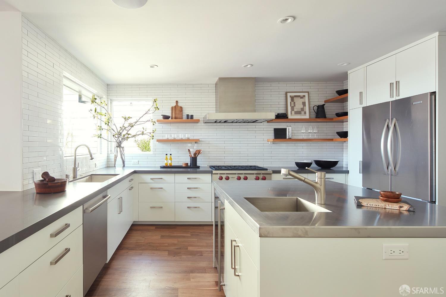 a kitchen with a sink dishwasher a refrigerator and white cabinets with wooden floor
