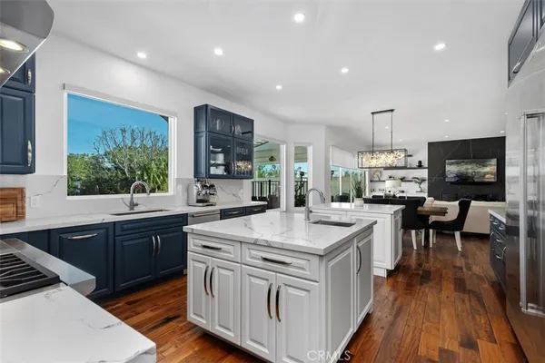 a kitchen with sink stove and white cabinets with wooden floor