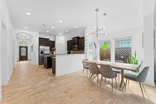 a kitchen with stainless steel appliances kitchen island granite countertop a refrigerator and a dining table