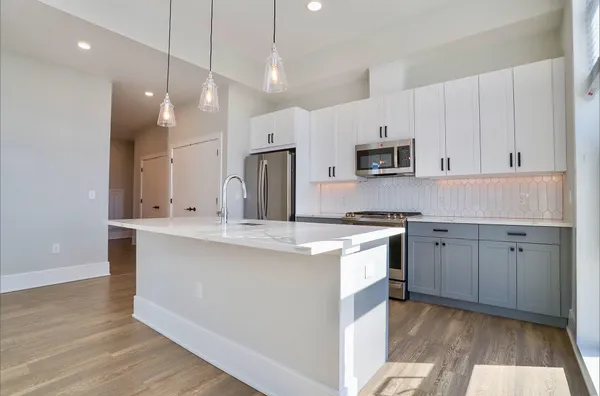 a kitchen with kitchen island white cabinets a sink a stove a refrigerator and a oven