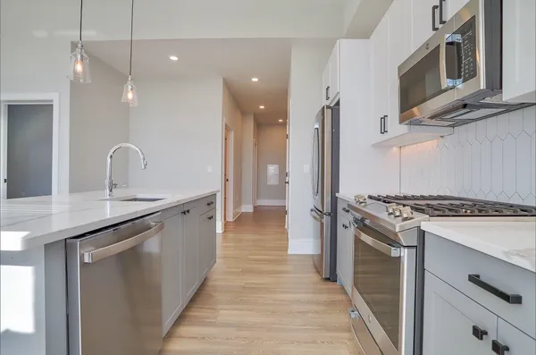 a kitchen with stainless steel appliances granite countertop a stove a sink and a refrigerator