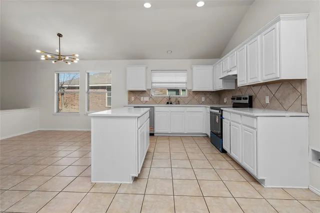a large white kitchen with a lot of cabinets and a wooden floor