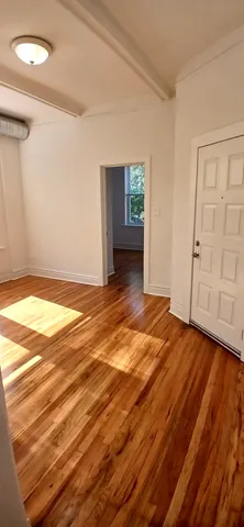 a view of an empty room with wooden floor and cabinet