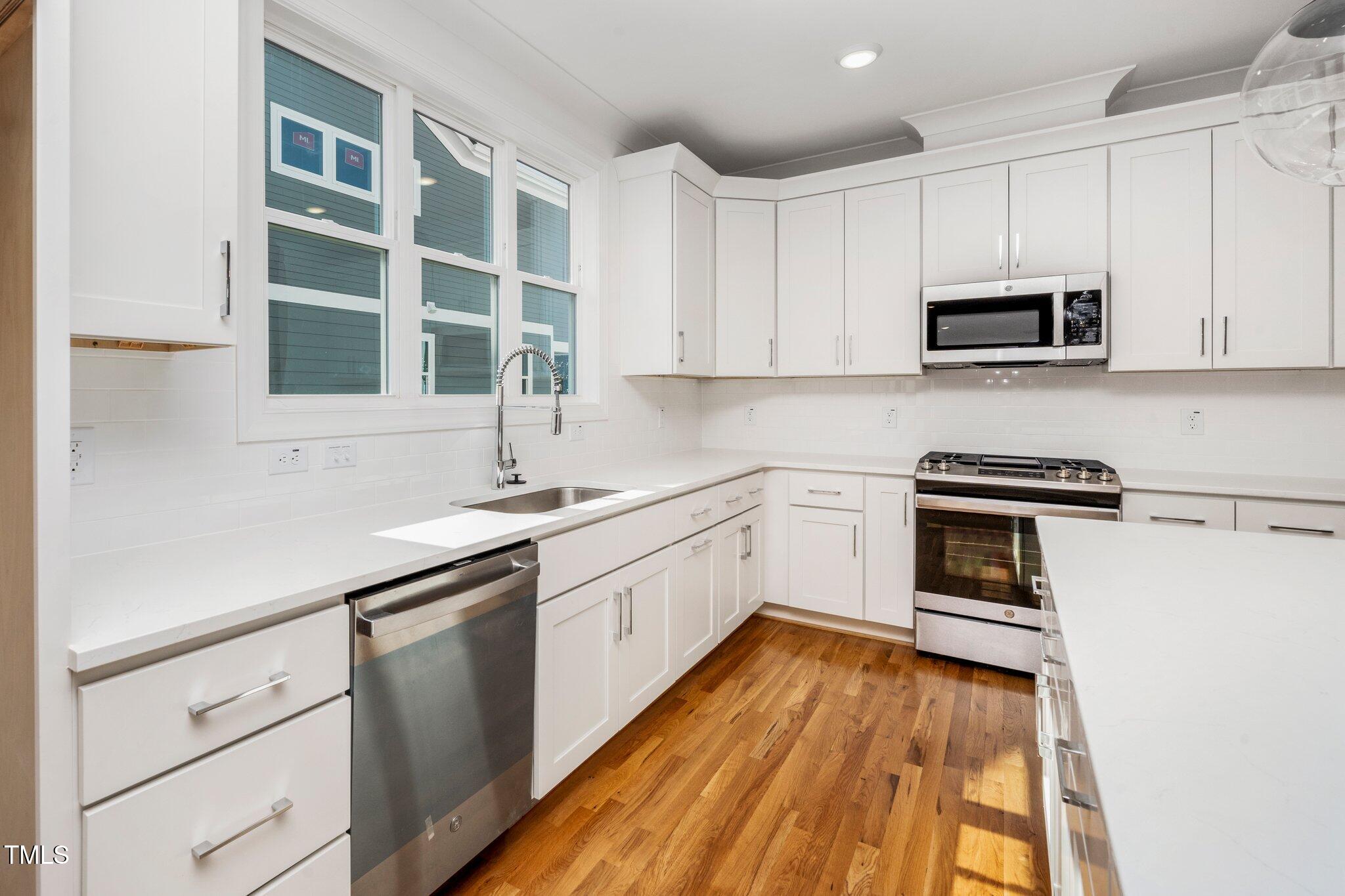 1215 Chaney Road Raleigh, NC 27606 - Photo 13 of 29 a kitchen with wooden cabinets and white appliances