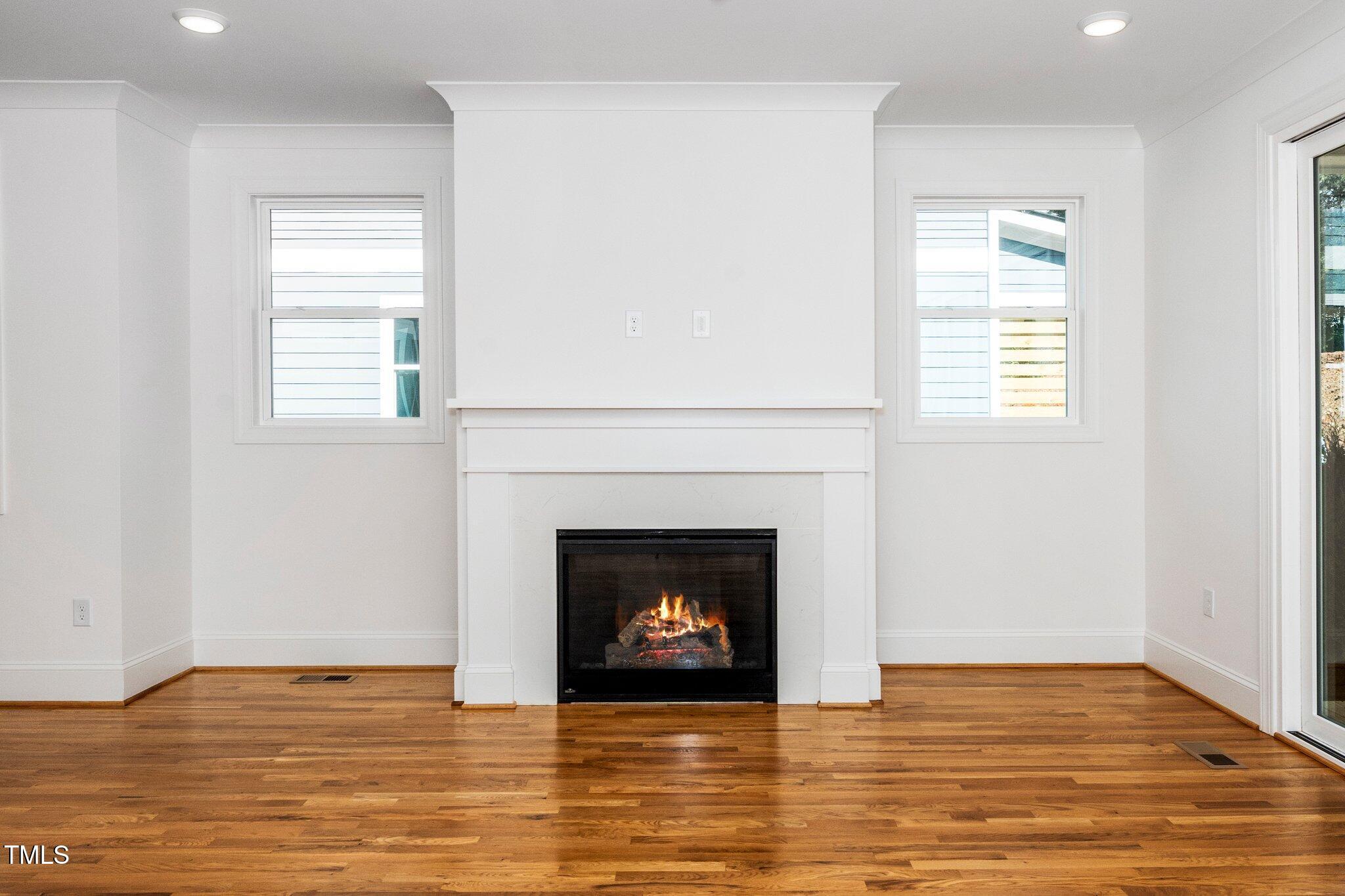 1215 Chaney Road Raleigh, NC 27606 - Photo 15 of 29 a view of an empty room with wooden floor and a fireplace