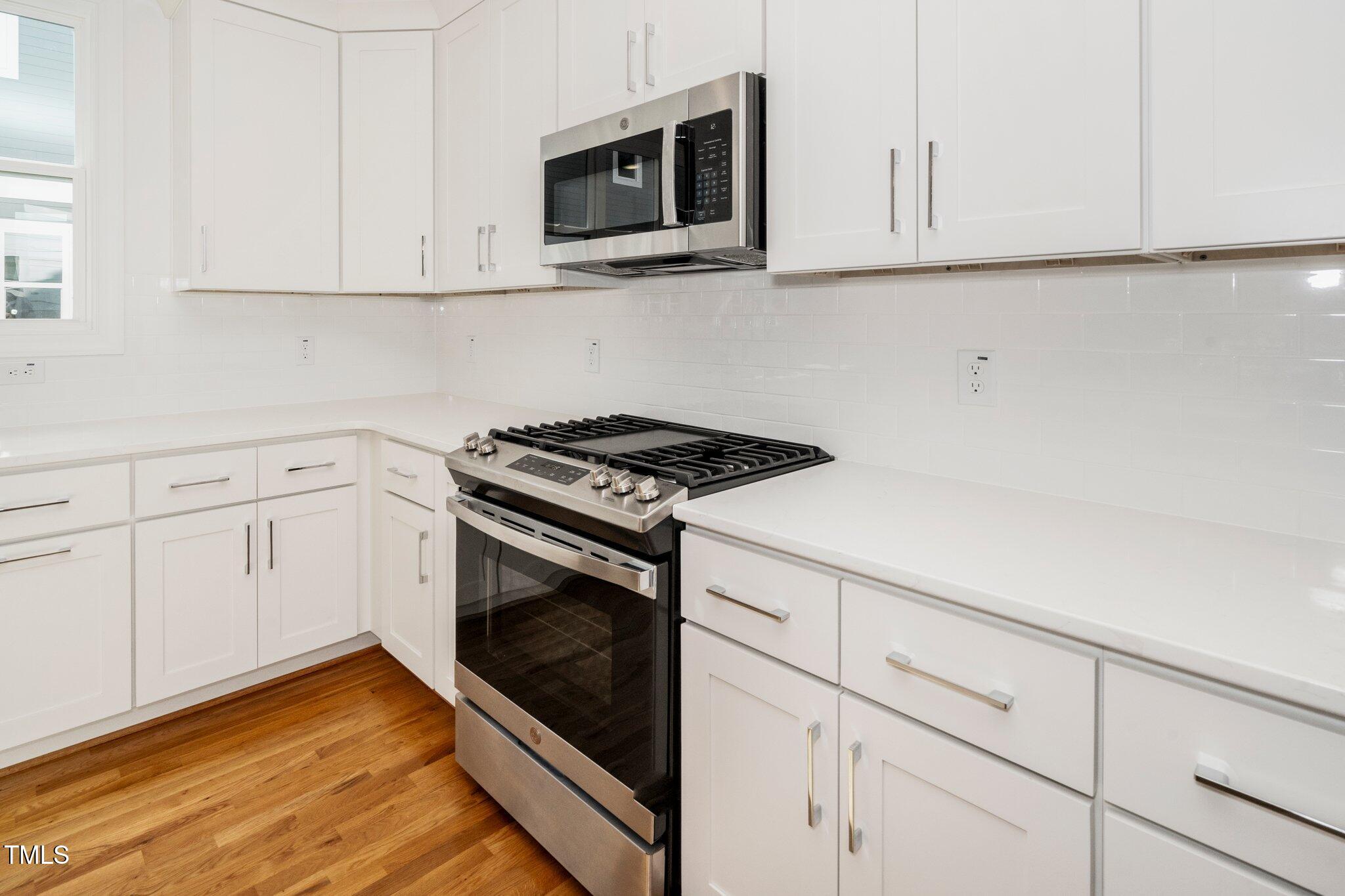 1215 Chaney Road Raleigh, NC 27606 - Photo 9 of 29 a kitchen with white cabinets stainless steel appliances and sink