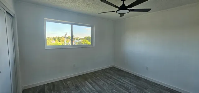 an empty room with a window and a fan