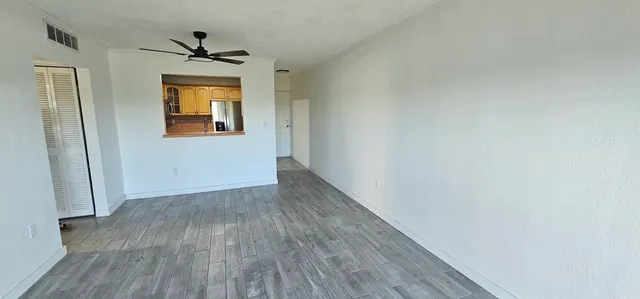a view of empty room with wooden floor and fan
