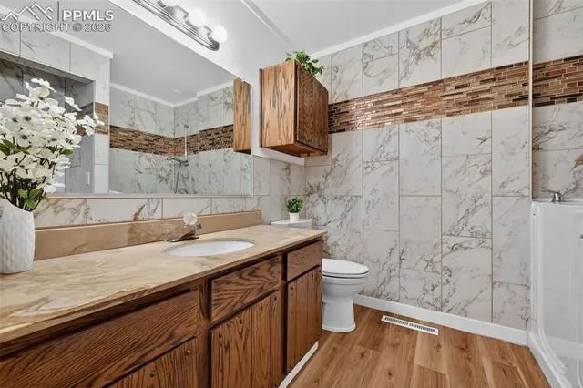 a bathroom with a granite countertop sink toilet and shower