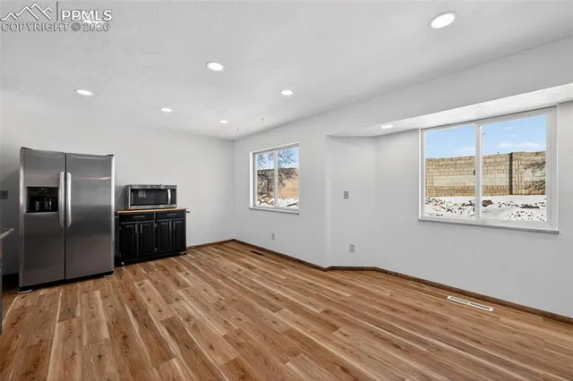 a view of a kitchen with wooden floor electronic appliances and windows