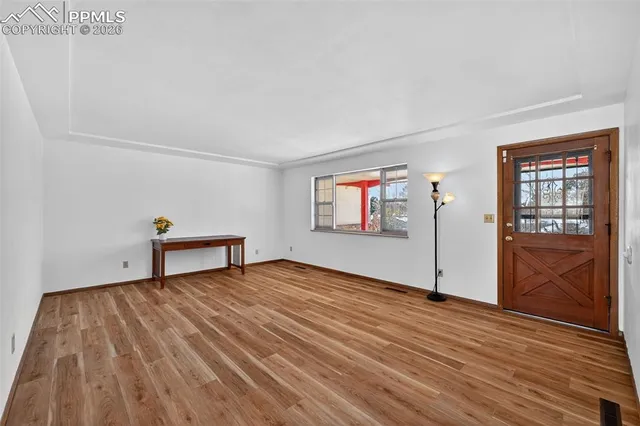 a view of an empty room with wooden floor and a window