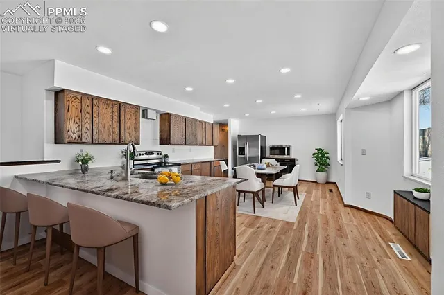 a kitchen with stainless steel appliances granite countertop table chairs sink and cabinets