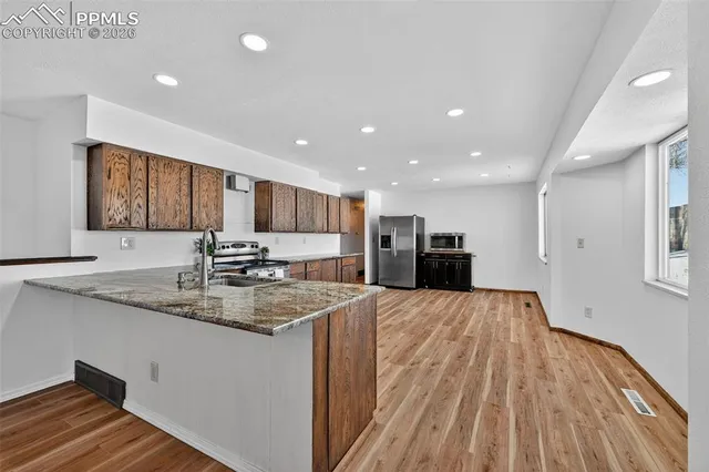 a large kitchen with stainless steel appliances granite countertop a large counter top a sink and a refrigerator