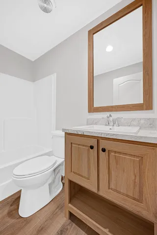 a bathroom with a granite countertop toilet sink and mirror