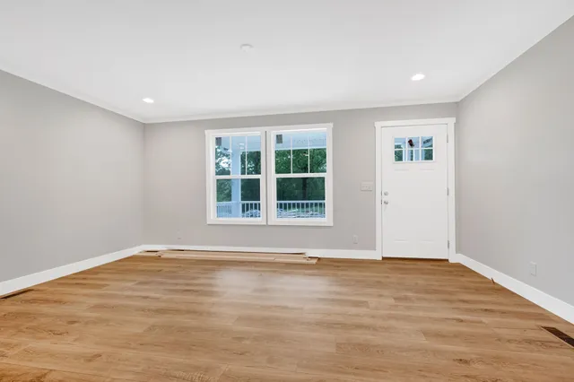 a view of an empty room with wooden floor and a window