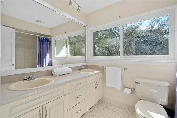 a bathroom with a granite countertop toilet sink and mirror next to a window