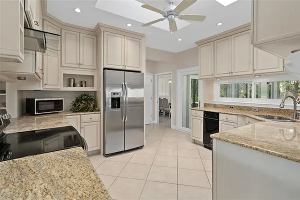 a kitchen with stainless steel appliances granite countertop a refrigerator a oven a sink and white cabinets