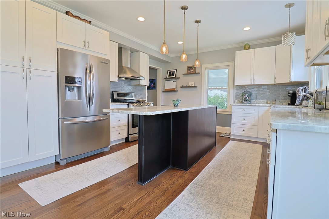 4376 Dover Center Road North Olmsted, OH 44070 - Photo 11 of 34 Kitchen with backsplash, stainless steel appliances, decorative light fixtures, and wall chimney exhaust hood