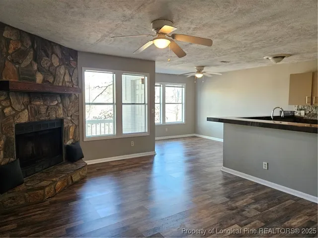 a view of wooden floor fire place and windows in an empty room