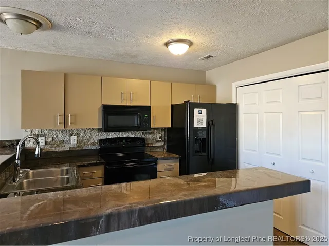 a kitchen with stainless steel appliances granite countertop a refrigerator and a stove top oven
