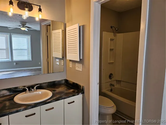 a bathroom with a granite countertop sink toilet mirror and bathtub
