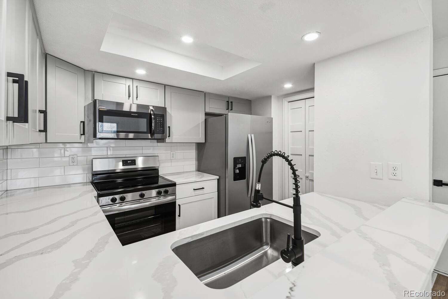 9041 Zephyr Court Broomfield, CO 80021 - Photo 14 of 35 a kitchen with stainless steel appliances a stove a sink dishwasher a refrigerator and a microwave