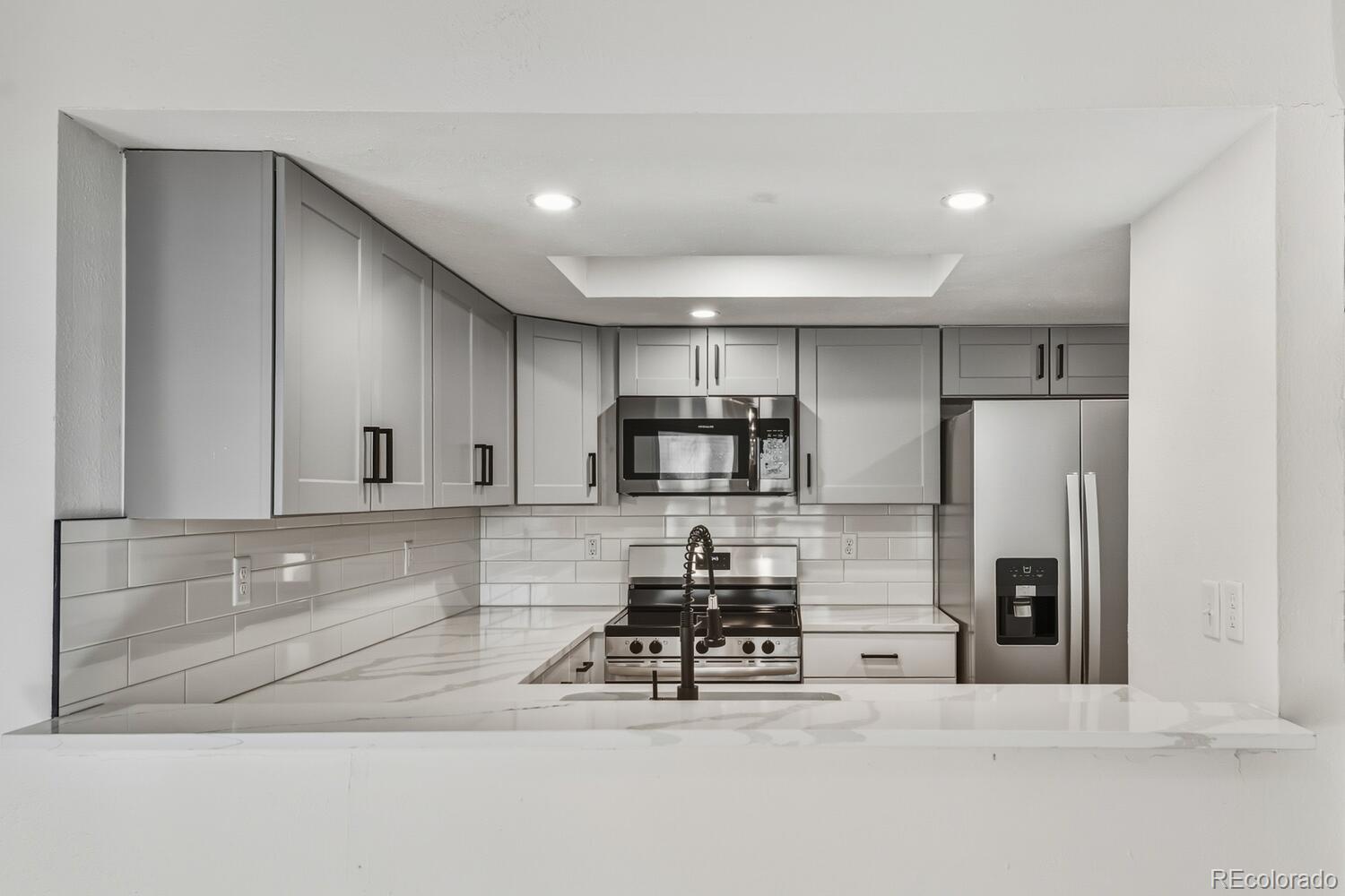 9041 Zephyr Court Broomfield, CO 80021 - Photo 15 of 35 a kitchen with stainless steel appliances kitchen island granite countertop a refrigerator and a stove top oven