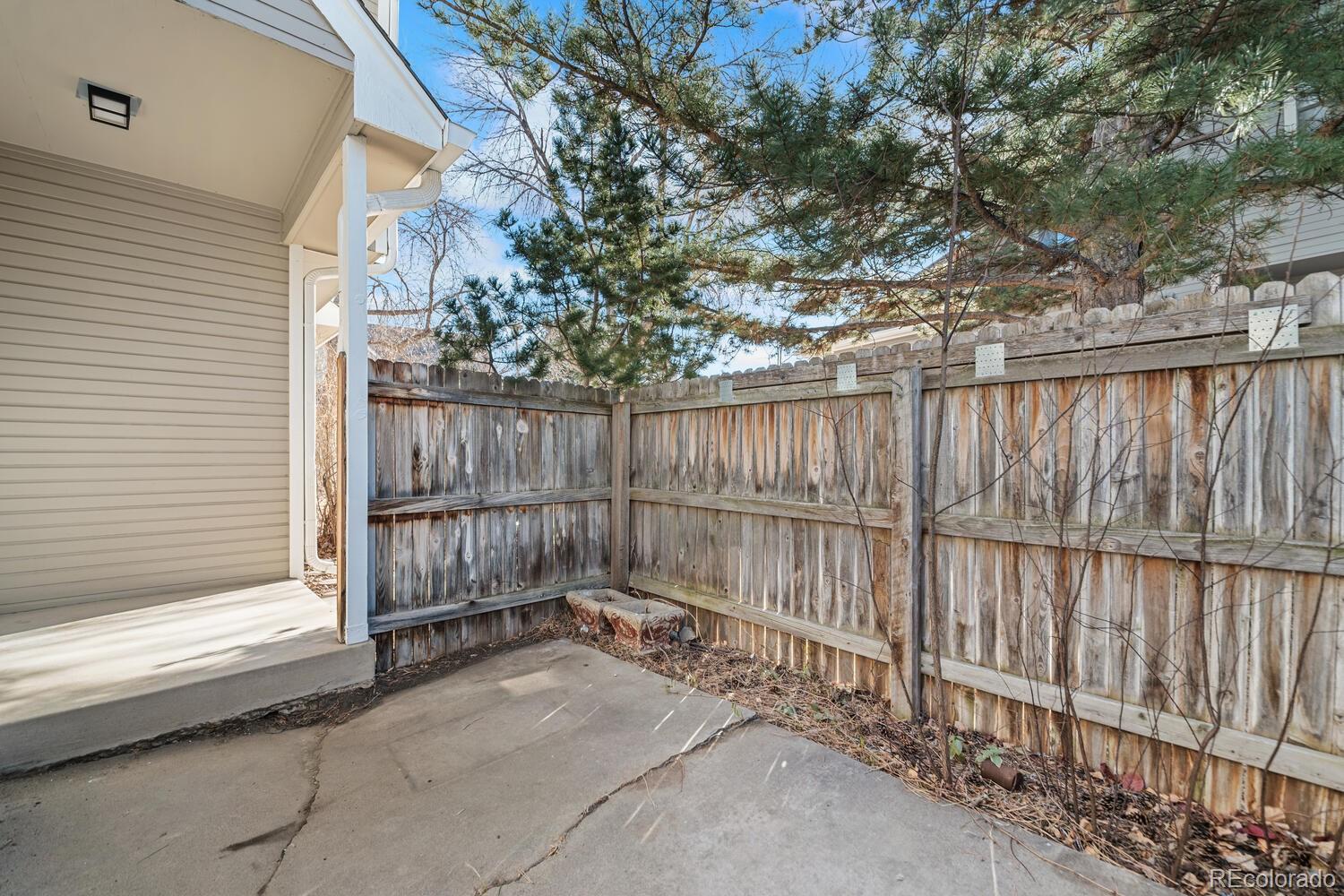 9041 Zephyr Court Broomfield, CO 80021 - Photo 32 of 35 a view of a backyard with a large tree and wooden fence