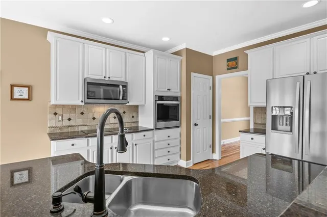 a kitchen with stainless steel appliances granite countertop a refrigerator and a stove top oven