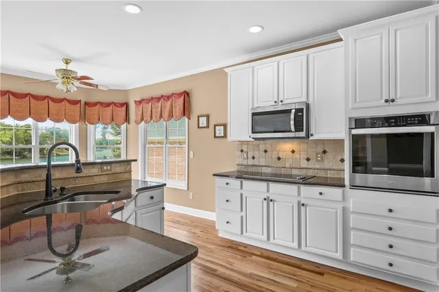 a kitchen with granite countertop a stove a sink and a microwave