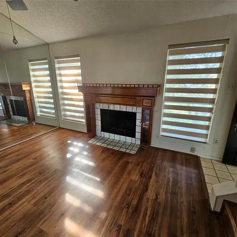a view of an empty room with wooden floor fireplace and a window