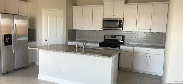 a kitchen with granite countertop a refrigerator stove and microwave