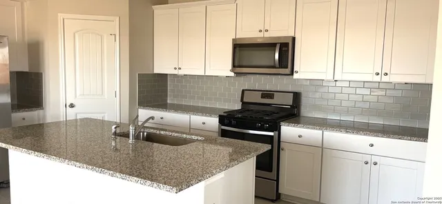 a kitchen with granite countertop a sink a stove and cabinets