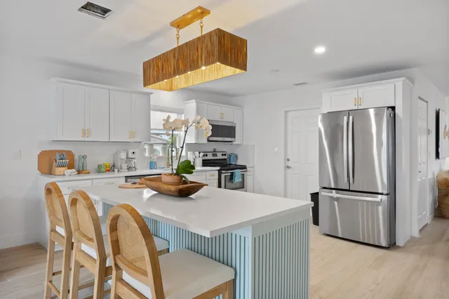 a kitchen with a refrigerator a stove a sink and white cabinets with wooden floor