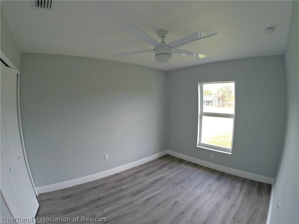 144 Lincoln Road Northwest Lake Placid, FL 33852 - Photo 16 of 19 an empty room with wooden floor fan and windows