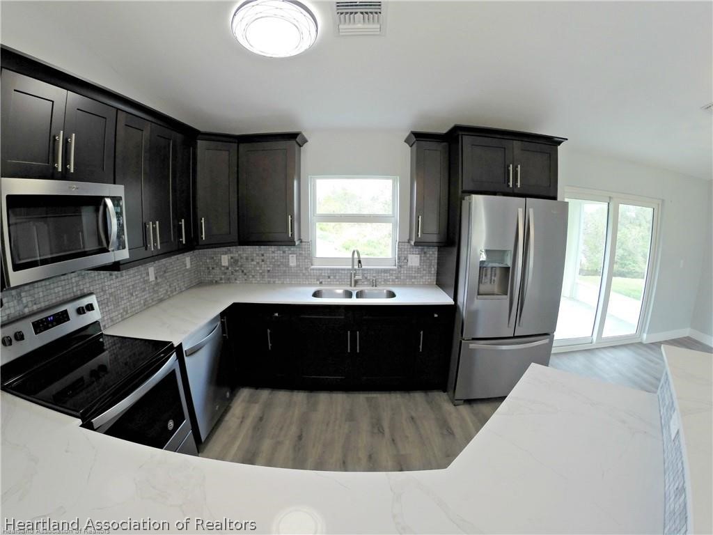 144 Lincoln Road Northwest Lake Placid, FL 33852 - Photo 7 of 19 a kitchen with a refrigerator a sink and wooden cabinets