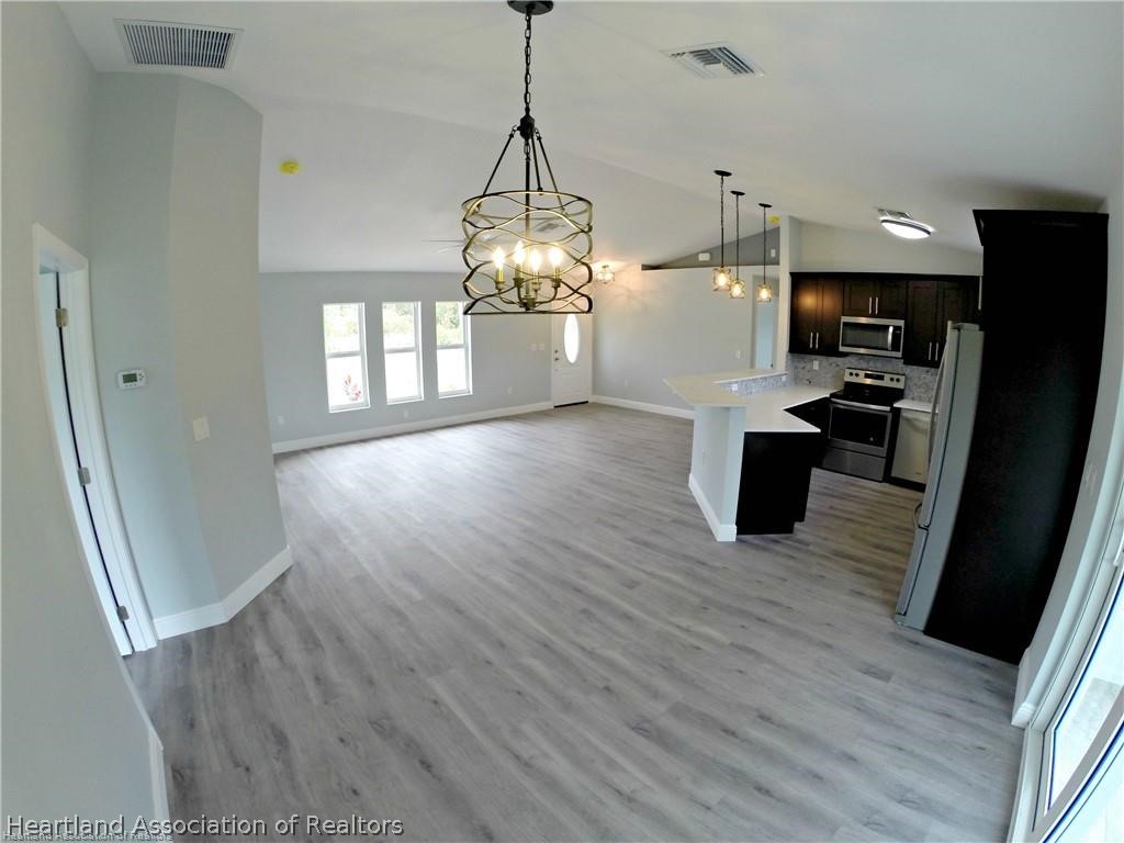 144 Lincoln Road Northwest Lake Placid, FL 33852 - Photo 9 of 19 a view of a kitchen and an empty room with wooden floor
