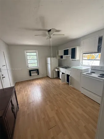 a view of a kitchen and an empty room with a window