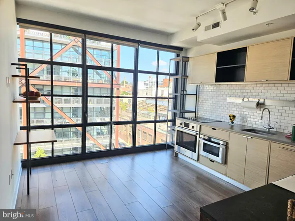 a kitchen with stainless steel appliances wooden floor and a large window