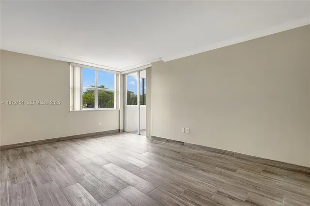 a view of an empty room with wooden floor and a window