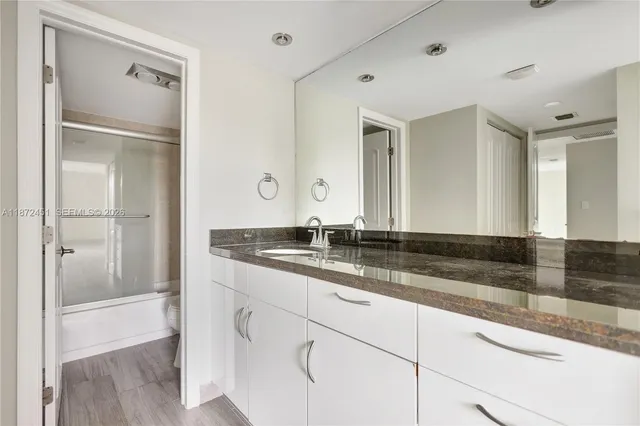 a bathroom with a granite countertop sink and a mirror