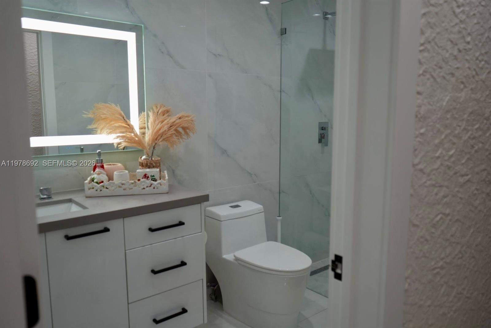 9351 Southwest 88th Terrace Miami, FL 33176 - Photo 49 of 73 a bathroom with a granite countertop toilet a sink and a mirror