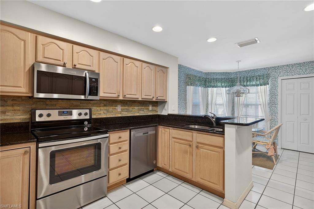242 Via Perignon, Unit 93 Naples, FL 34119 - Photo 12 of 20 a kitchen with granite countertop a stove sink and microwave