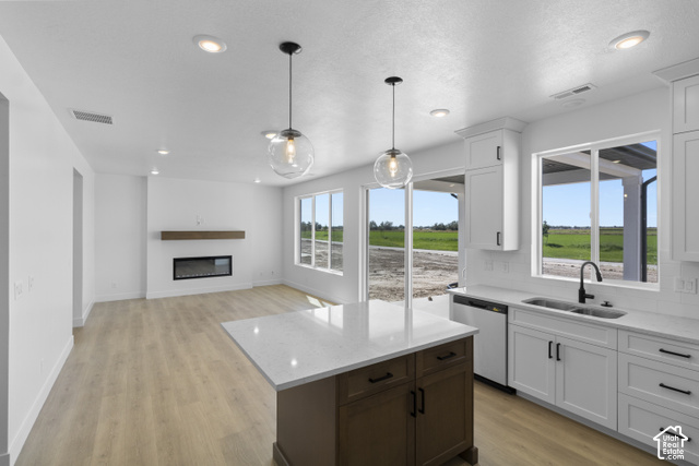 537 South 1150 West Logan, UT 84321 - Photo 16 of 33 Open-concept living area featuring wood-finish flooring, a contemporary fireplace with a wood mantle, recessed lighting, and a kitchen island with a light-colored countertop