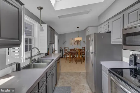 a kitchen with stainless steel appliances granite countertop a sink a stove and a refrigerator with wooden floor
