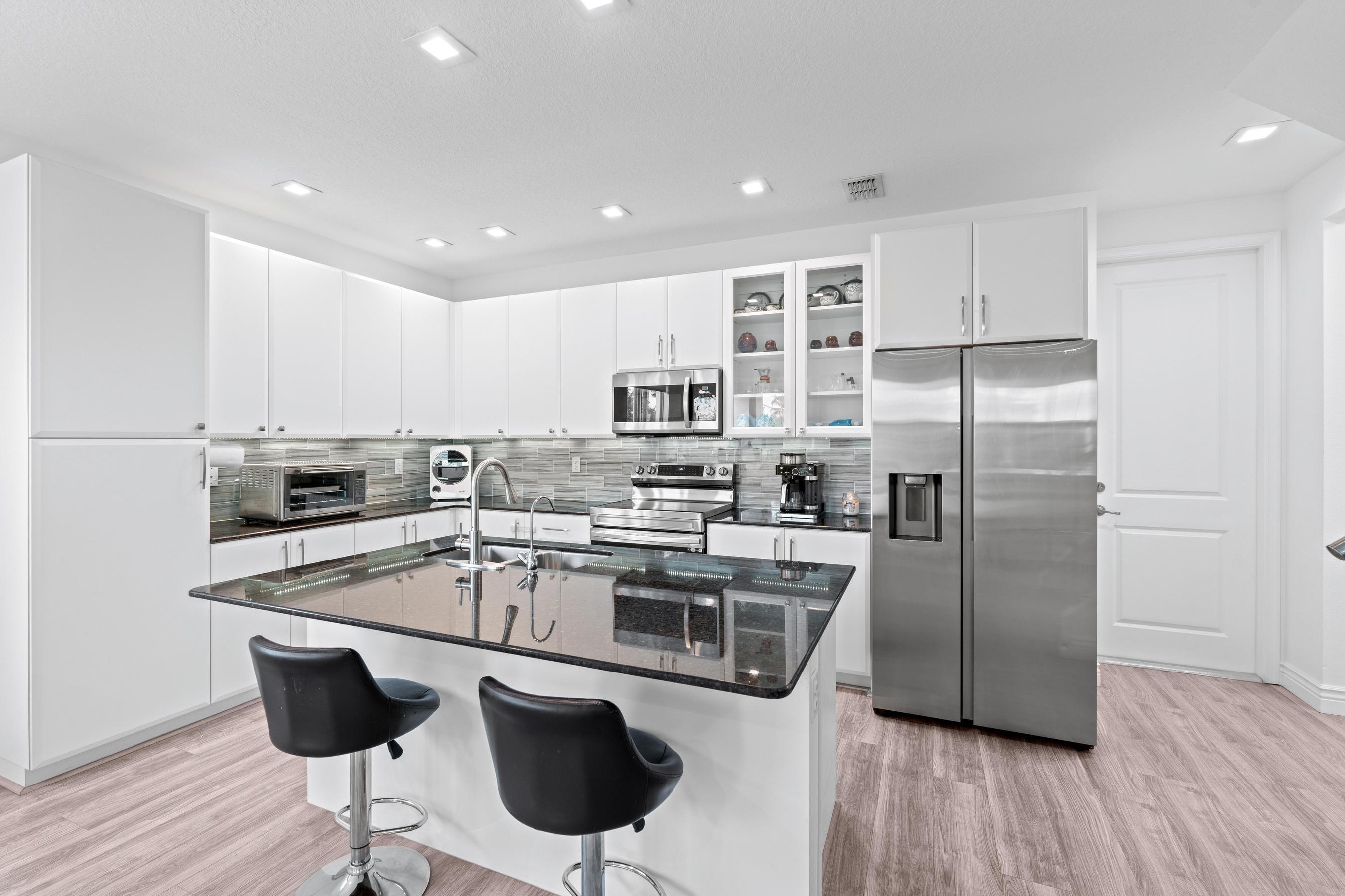 5010 Northwest 16th Way Boca Raton, FL 33431 - Photo 7 of 42 a kitchen with stainless steel appliances granite countertop a stove a refrigerator a sink a dining table and chairs