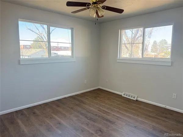 a view of an empty room with wooden floor and a window