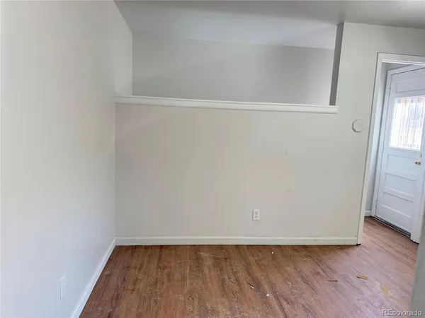 a view of an empty room with wooden floor and closet